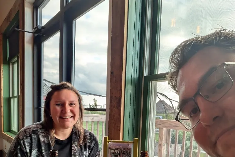 Two people at a taproom table with Wisconsin soda bottles